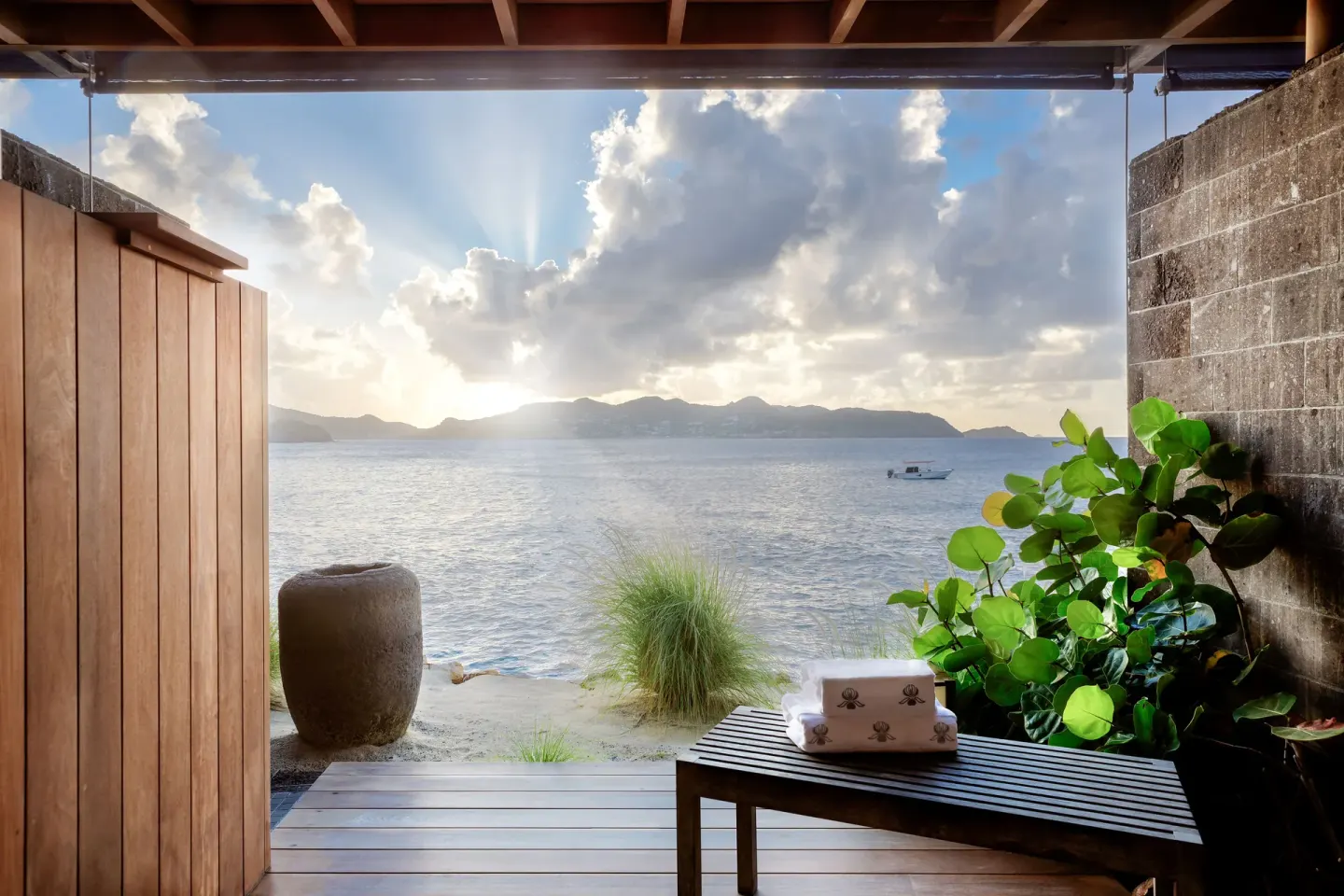 A spa deck with towels and sea views opens toward the beach at Christopher Hotel.