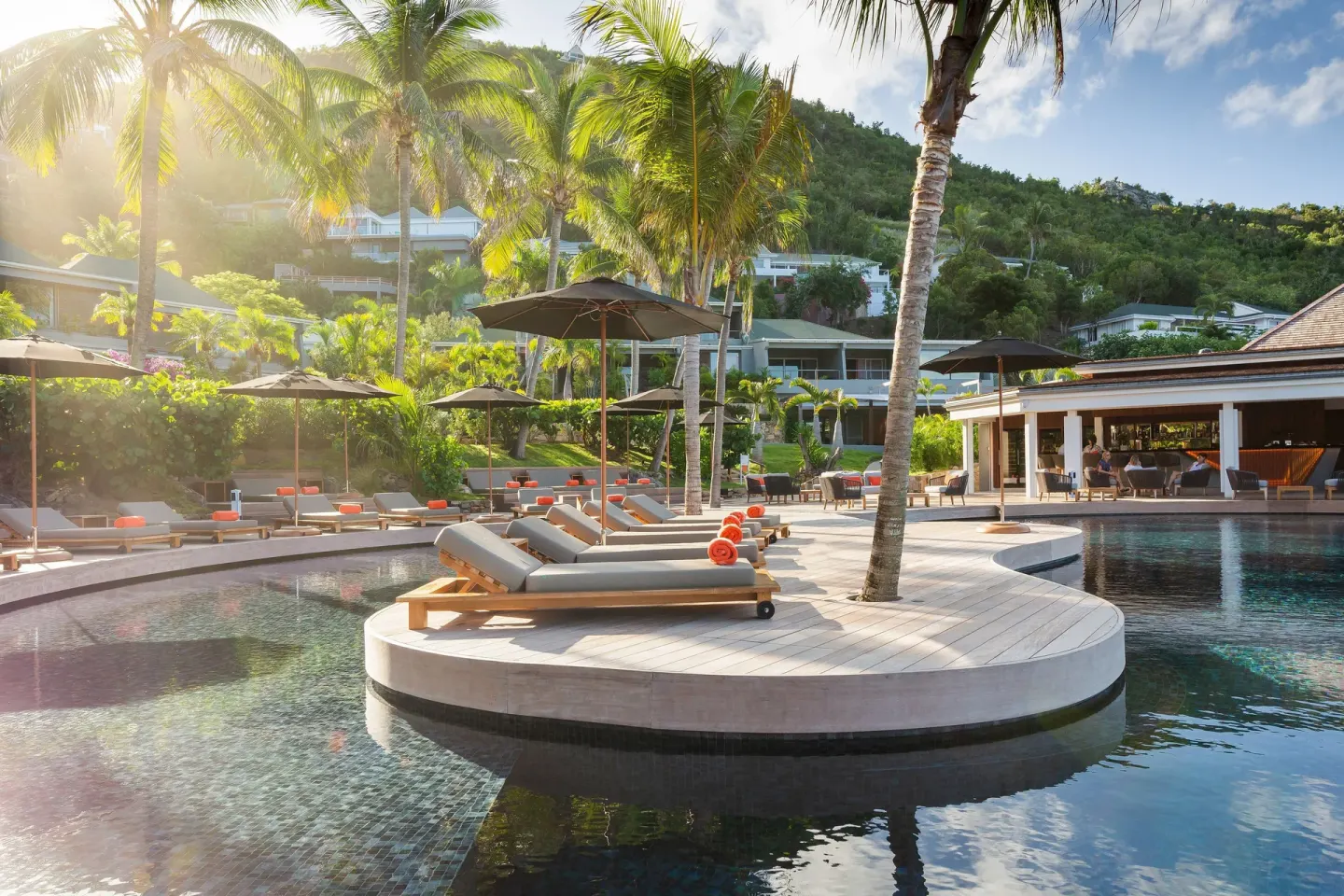 Sunlit pool deck with loungers, palms, and resort buildings at Christopher Hotel.