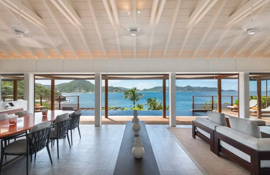 Villa lounge and dining area opening to an infinity pool at Christopher Hotel.