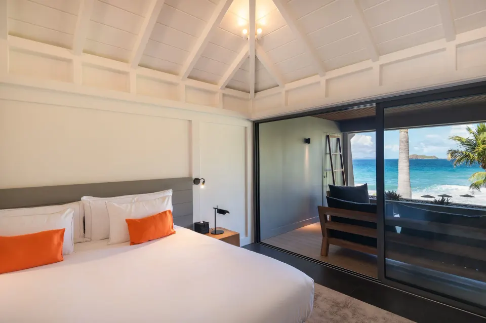 Deluxe room king bed beside sliding doors to an ocean balcony at Christopher Hotel.