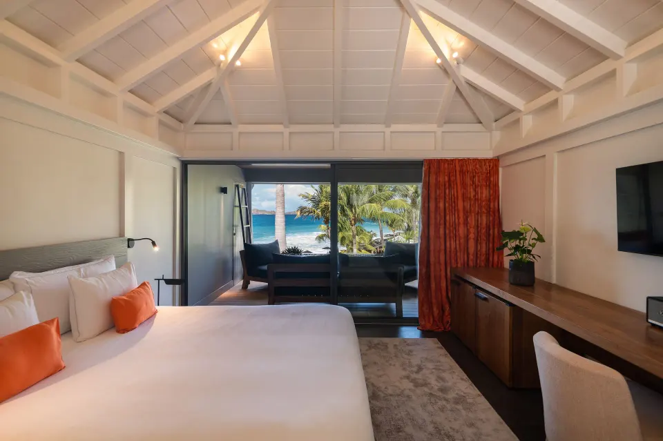 Deluxe room bed and ocean-facing balcony at Christopher Hotel.
