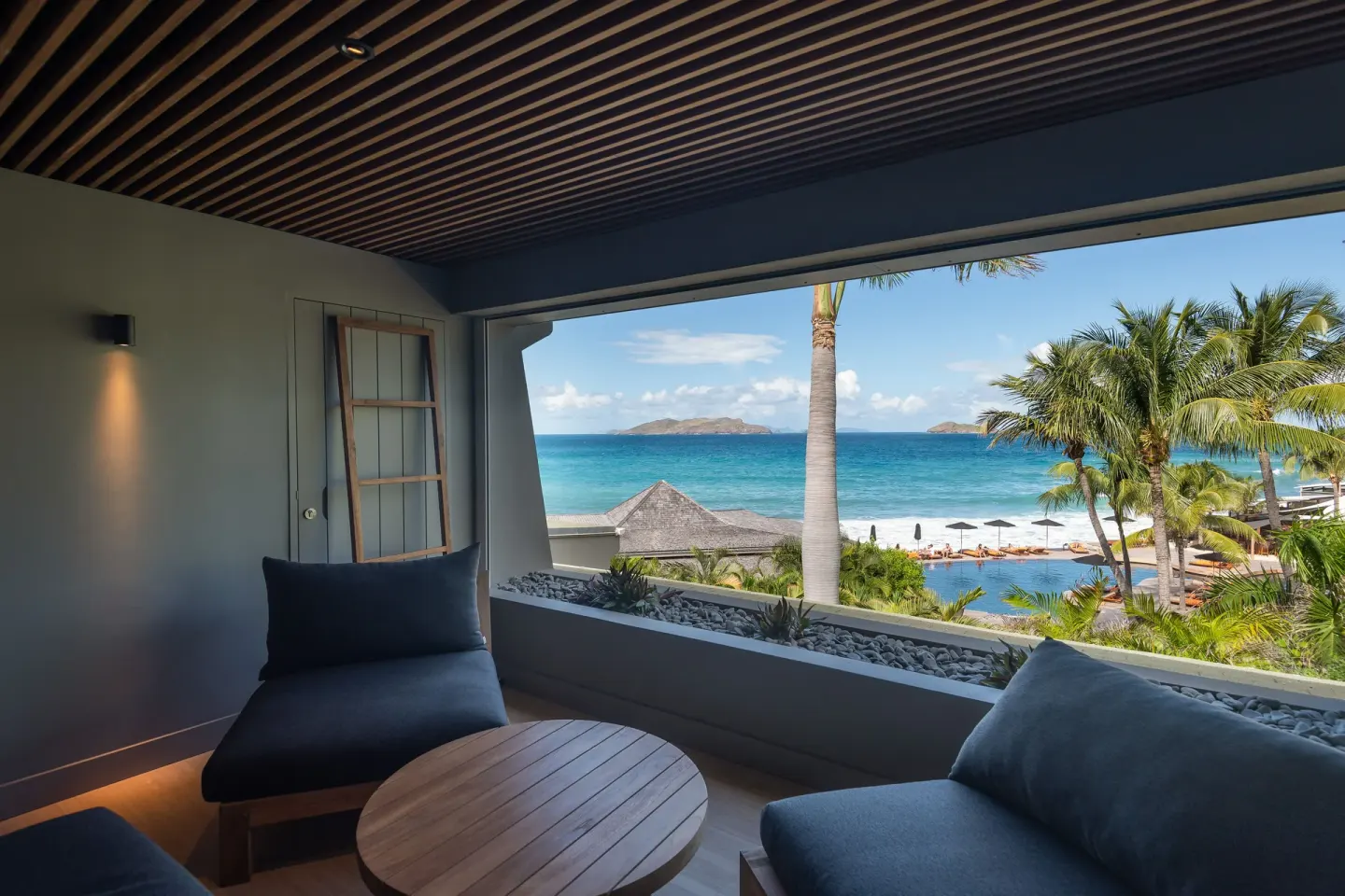 Covered balcony seating with ocean and pool views at Christopher Hotel.