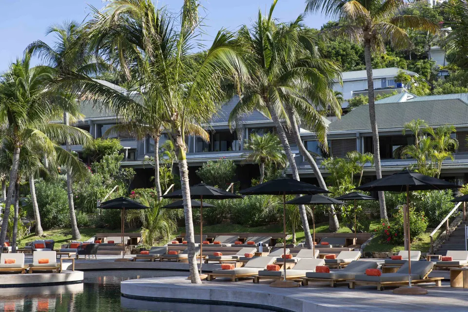 Christopher Hotel pool deck with loungers, umbrellas, palms and hillside rooms.