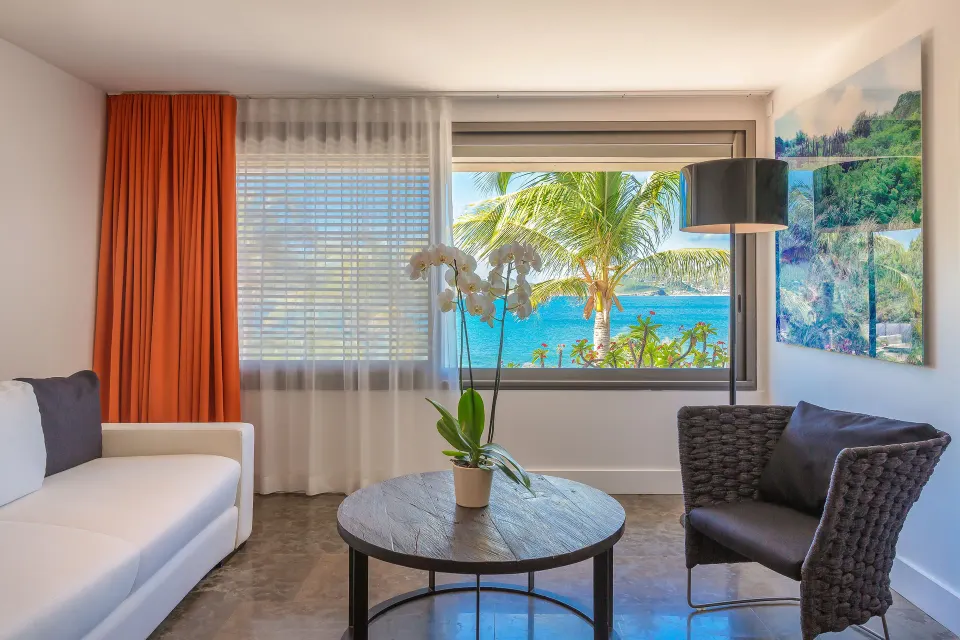 Junior Suite ocean sitting area with sofa, chair, table and sea view at Christopher Hotel.