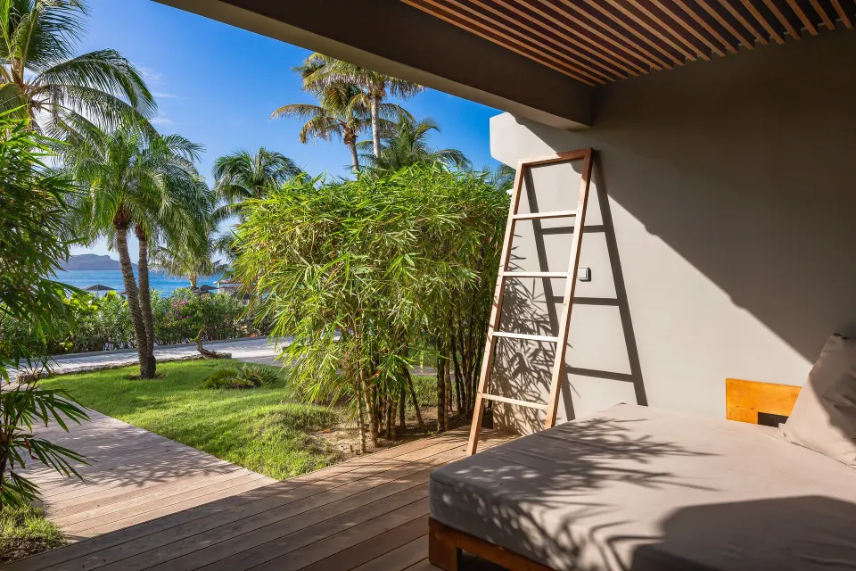 Private terrace with daybed, palms, and ocean glimpse at Christopher Hotel.