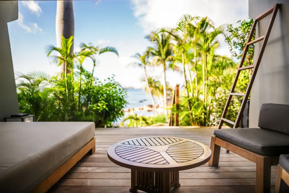Ocean Spa Suite terrace with loungers, table, palms, and sea view at Christopher Hotel.
