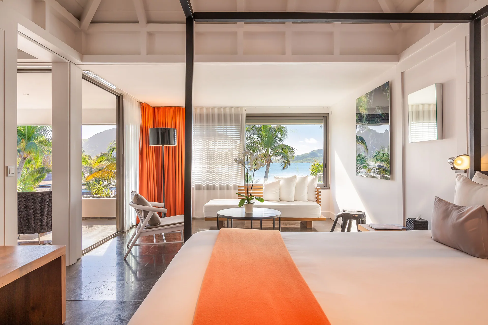 Ocean suite bedroom with bed, lounge seating, balcony, and water views at Christopher Hotel.