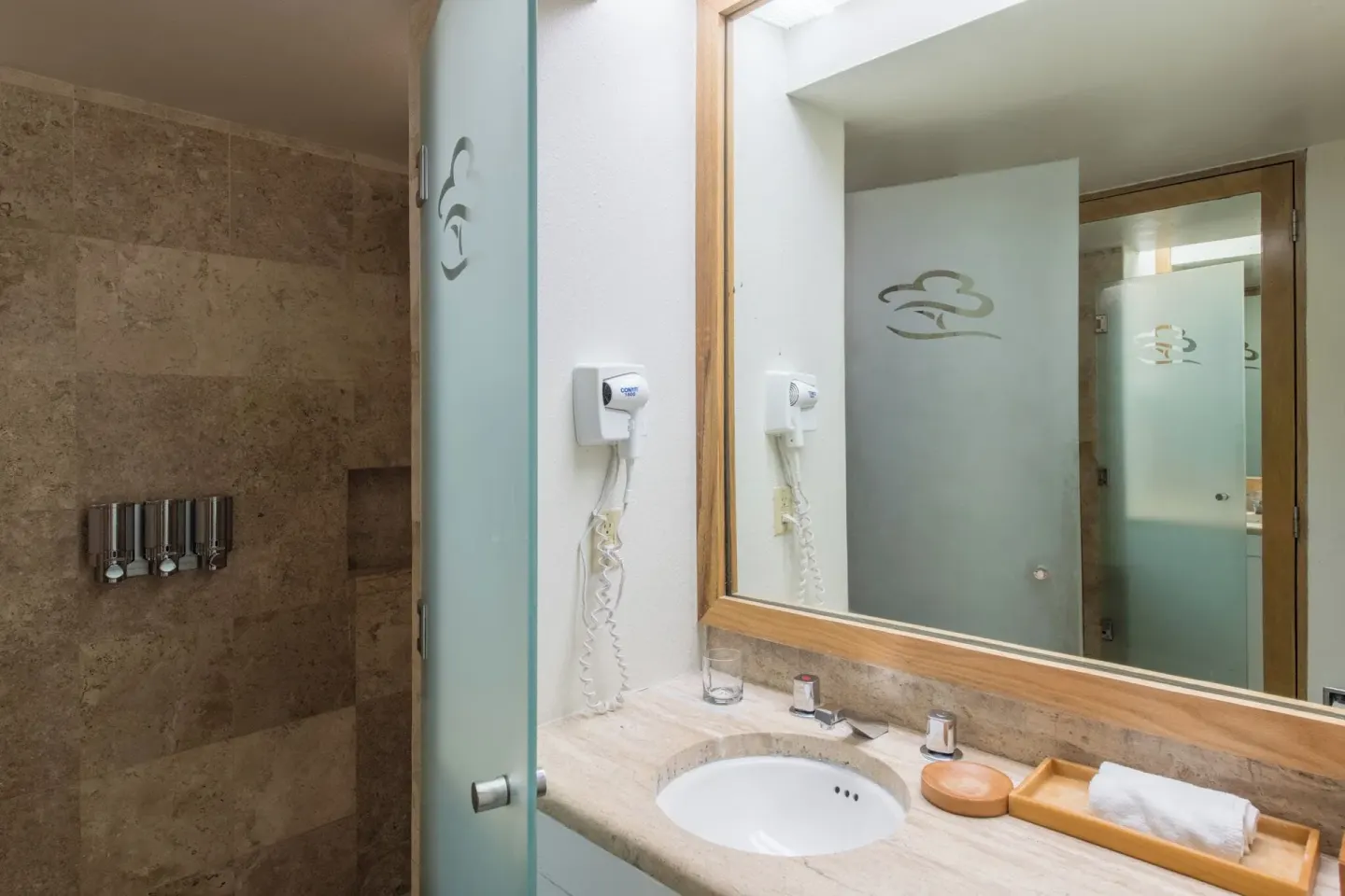 Bathroom sink and glass shower with stone tile at Club Regina Cancun.