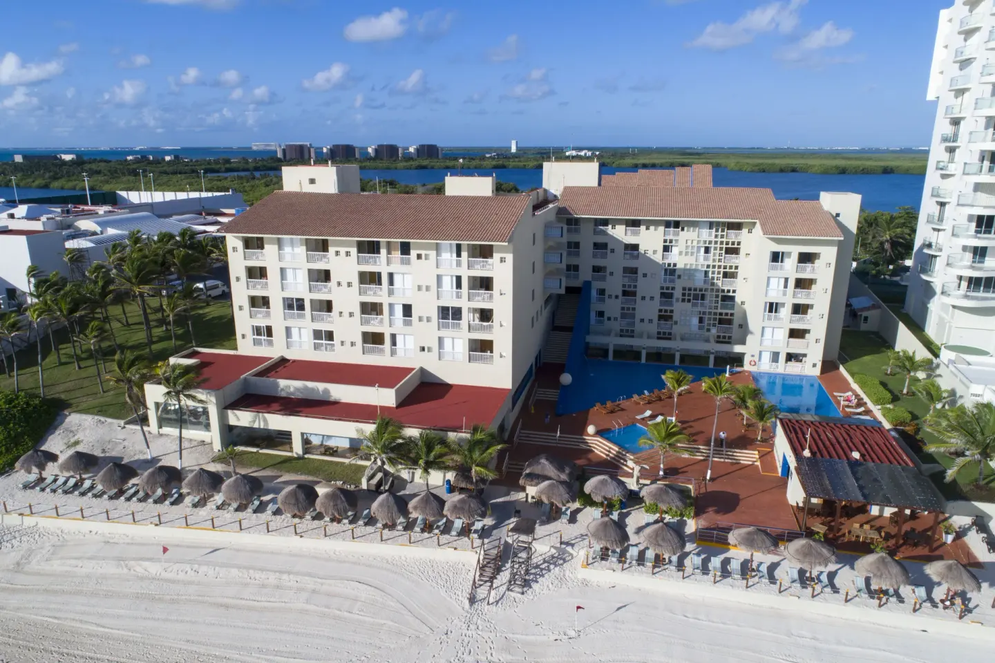 Aerial view of the beachfront buildings, pool deck and palapas at Club Regina Cancun.