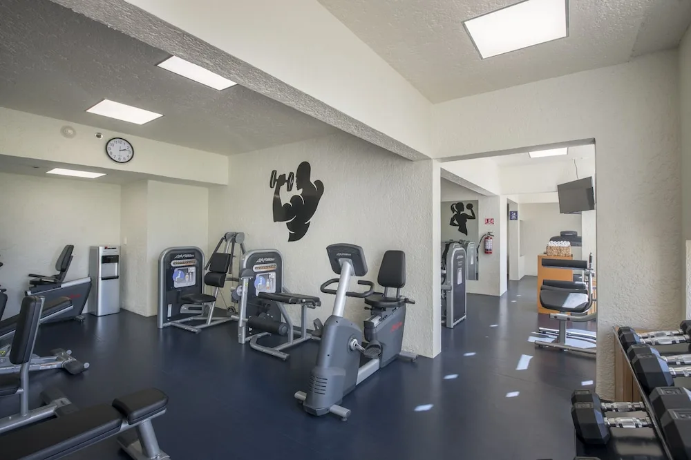 Fitness room with cardio machines, weights, and strength equipment at Club Regina Cancun.