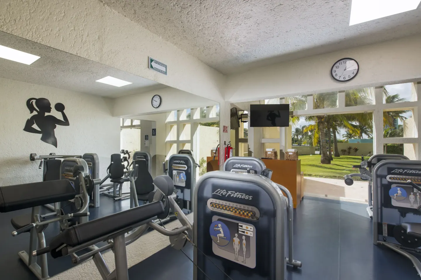 Fitness room with weight machines, mirrors, and garden windows at Club Regina Cancun.