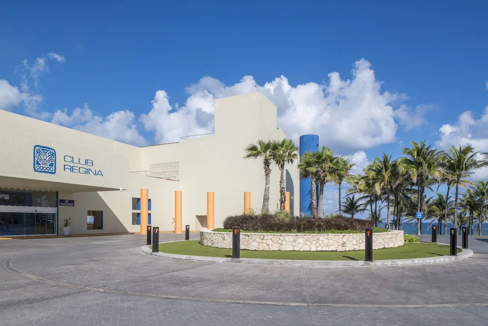 Front entrance driveway with Club Regina Cancun signage and palm trees.