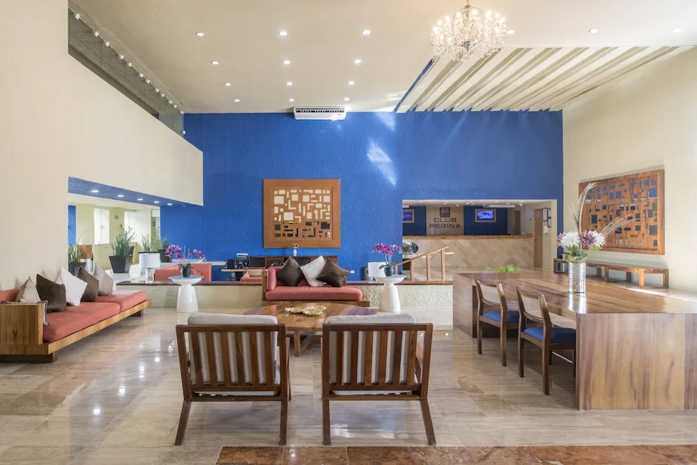 Lobby seating area with blue accent wall and reception desk at Club Regina Cancun.