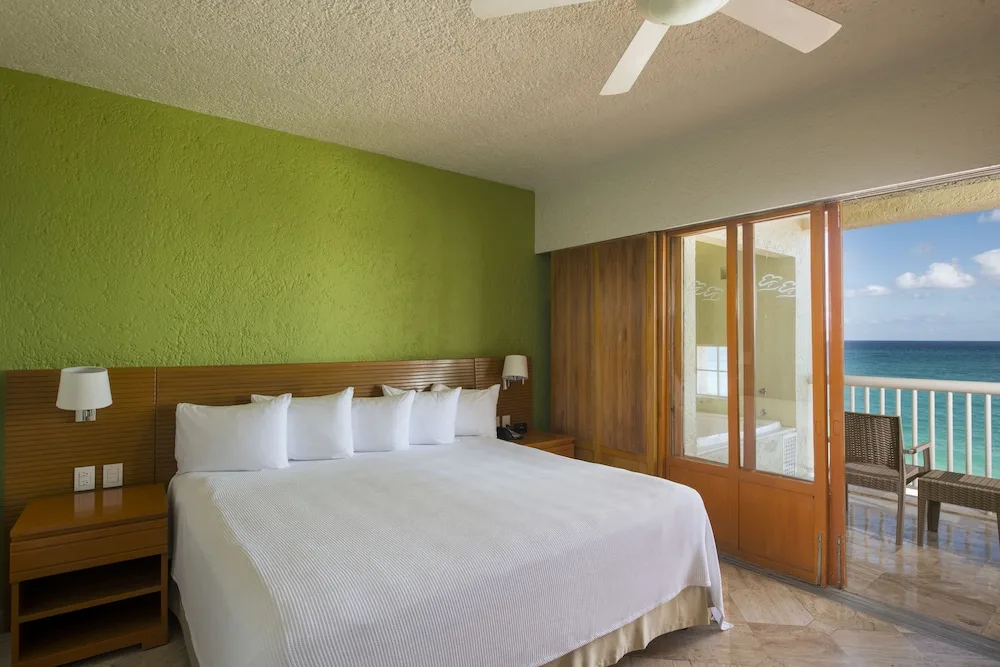 Ocean-view guest room with a king bed and balcony at Club Regina Cancun.