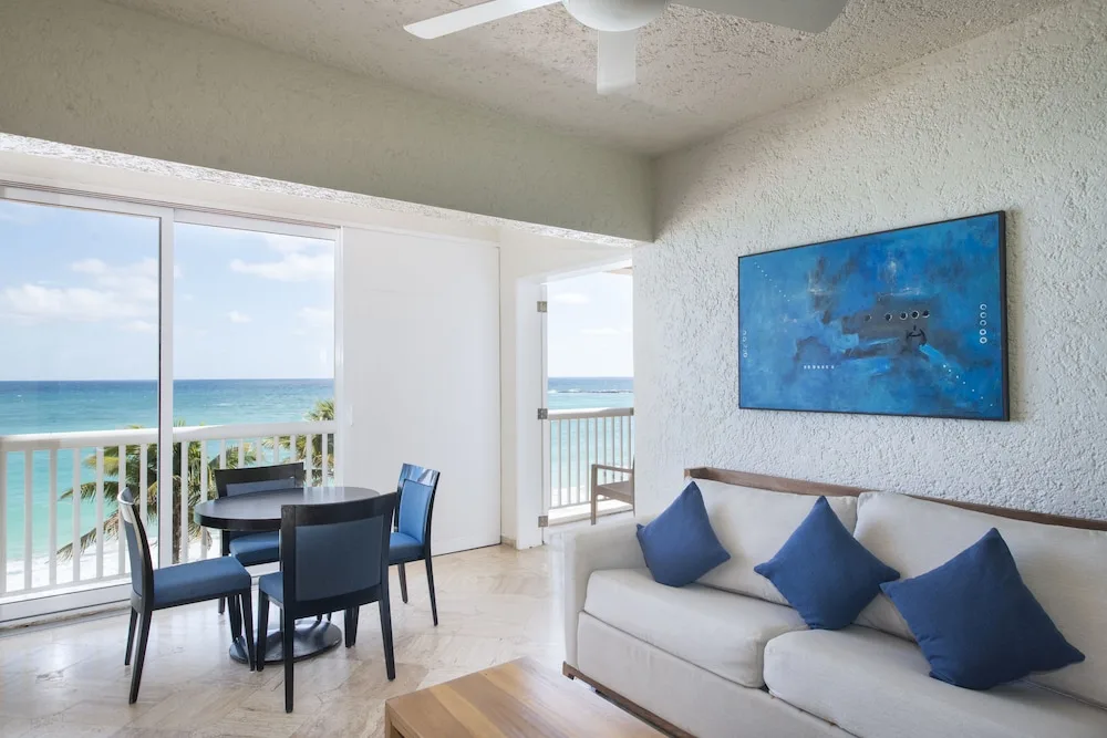 Ocean-view living area with sofa, dining table and balcony at Club Regina Cancun.