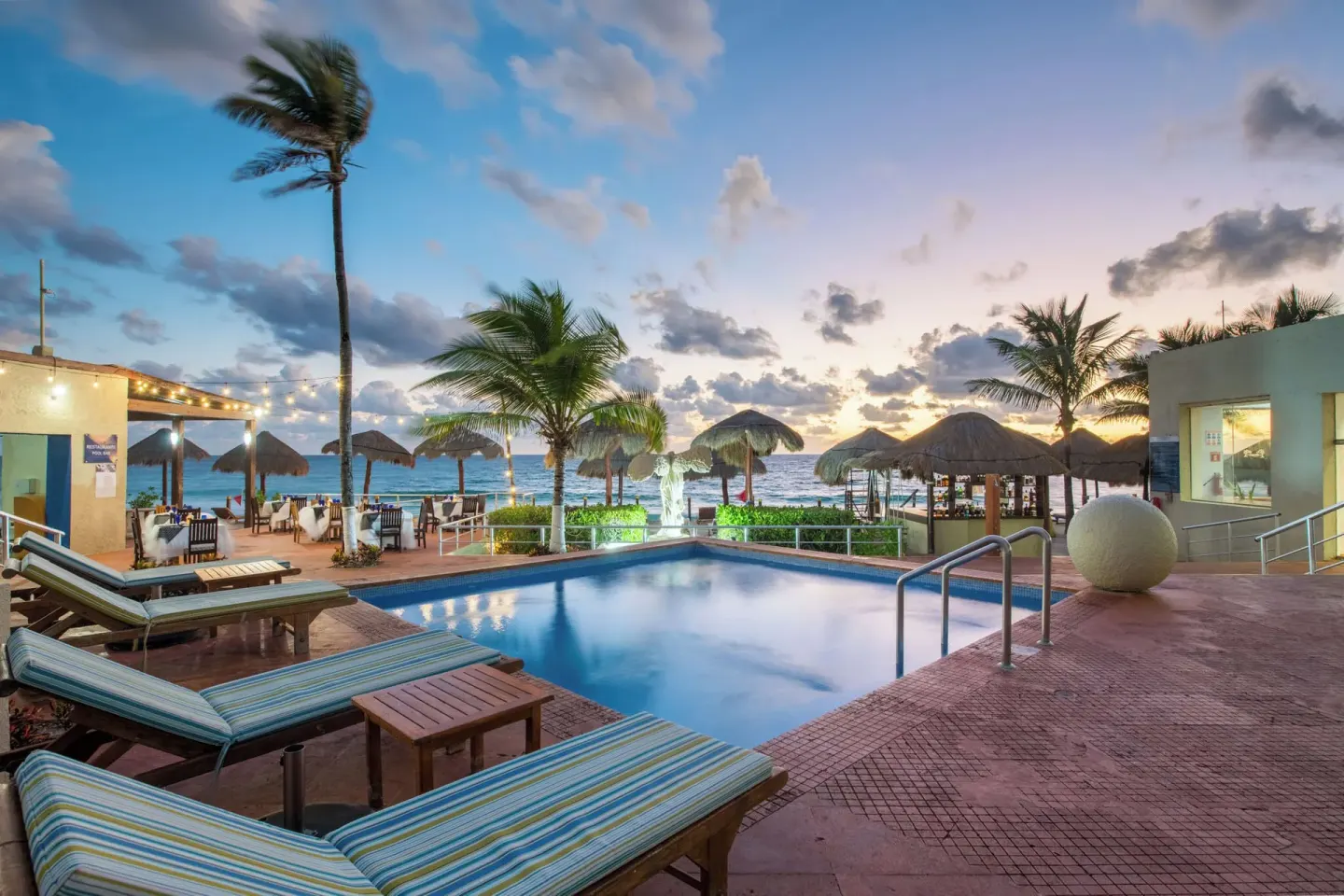Pool terrace with lounge chairs and ocean beyond at Club Regina Cancun.