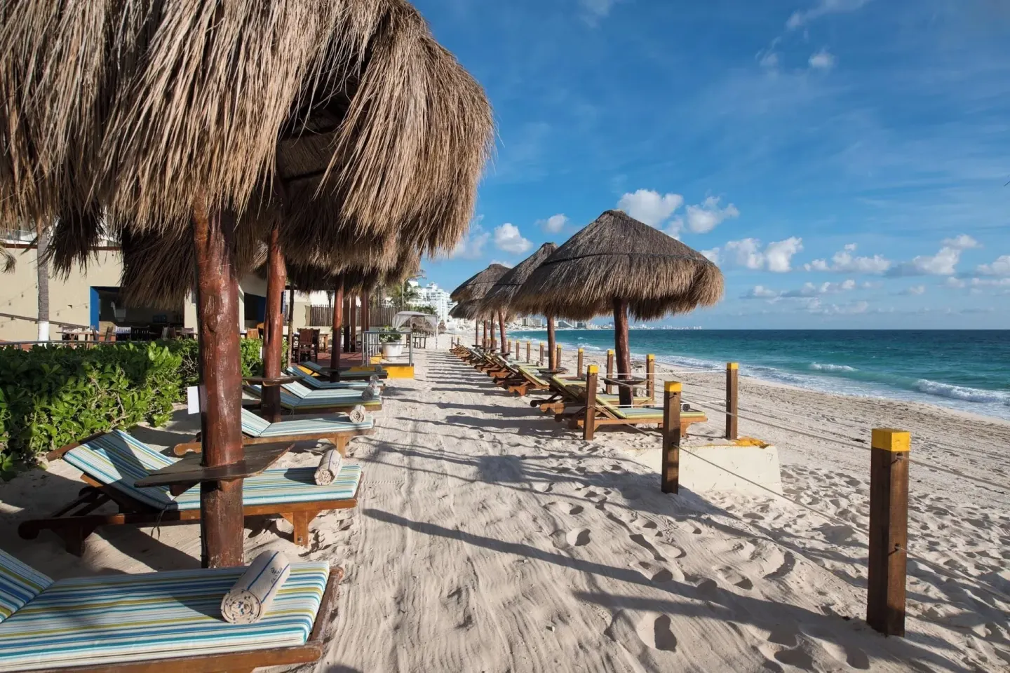 Sandy beachfront with palapas, loungers, and blue water at Club Regina Cancun.