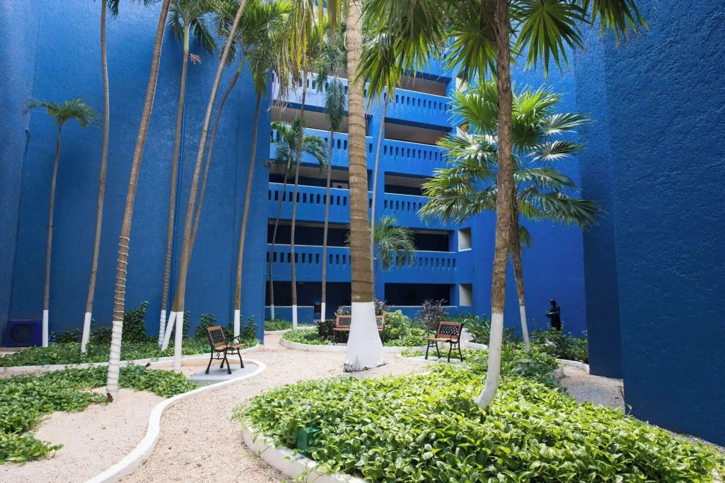 Palm-lined garden courtyard between blue resort buildings at Club Regina Cancun.