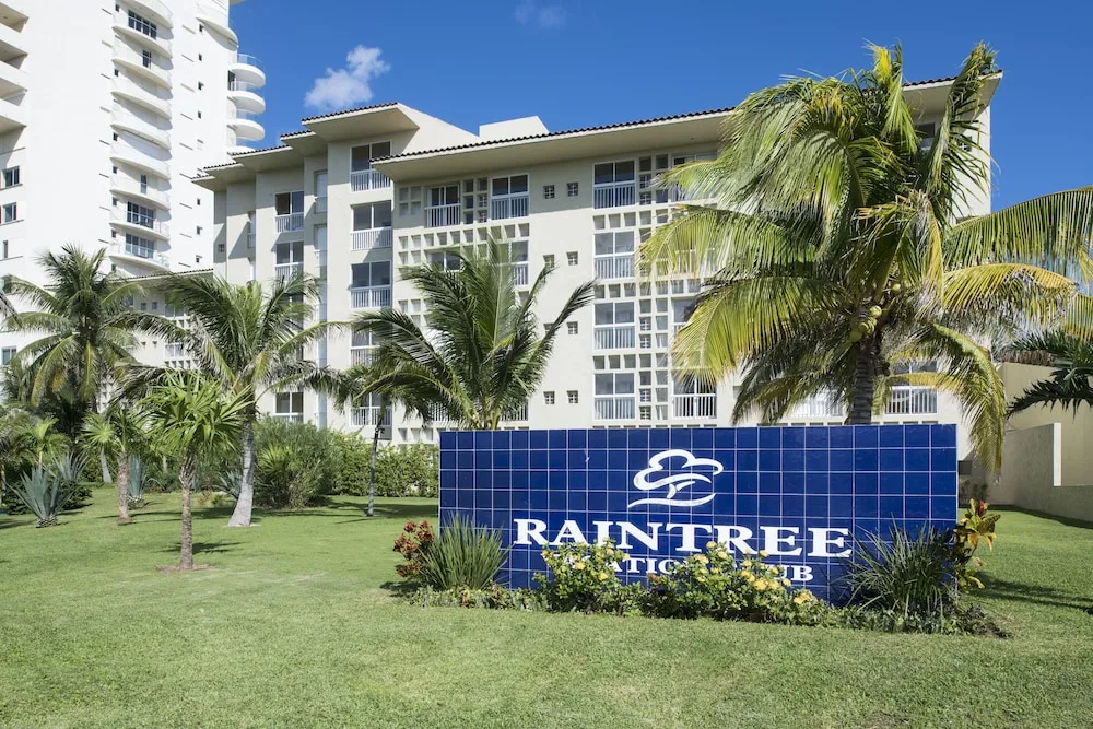 Palm lawn and blue tile resort sign outside Club Regina Cancun.