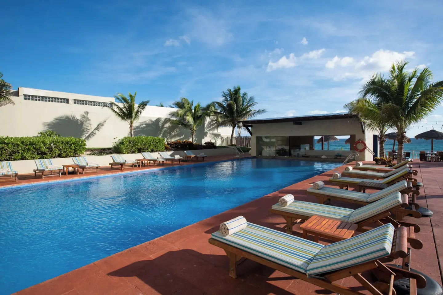 Pool deck with loungers and palm trees at Club Regina Cancun.
