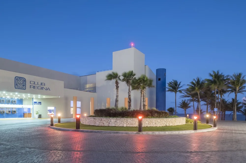 Illuminated resort entrance and palm-lined drive at Club Regina Cancun.