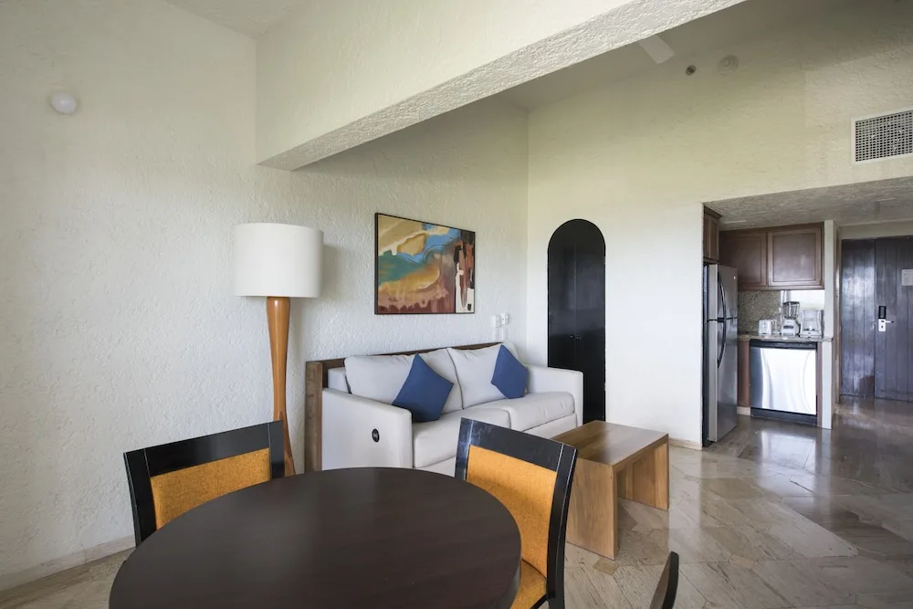 Living and dining area with kitchenette inside a suite at Club Regina Cancun.