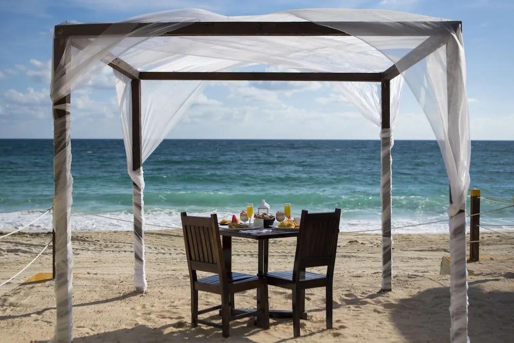 Beachside private dining setup beneath a white canopy at Club Regina Cancun.