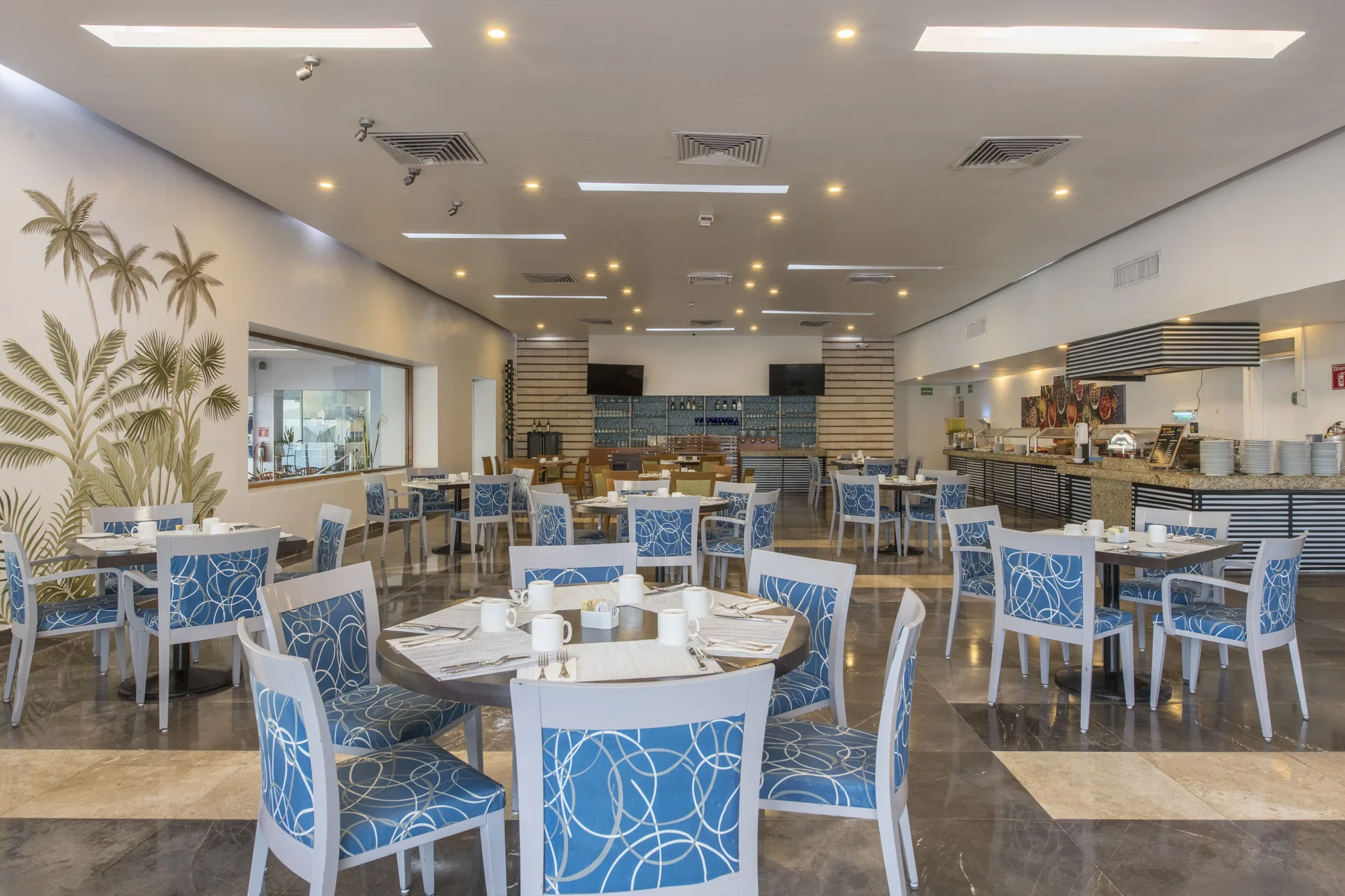 Bright buffet dining room with blue chairs at Club Regina Cancun.