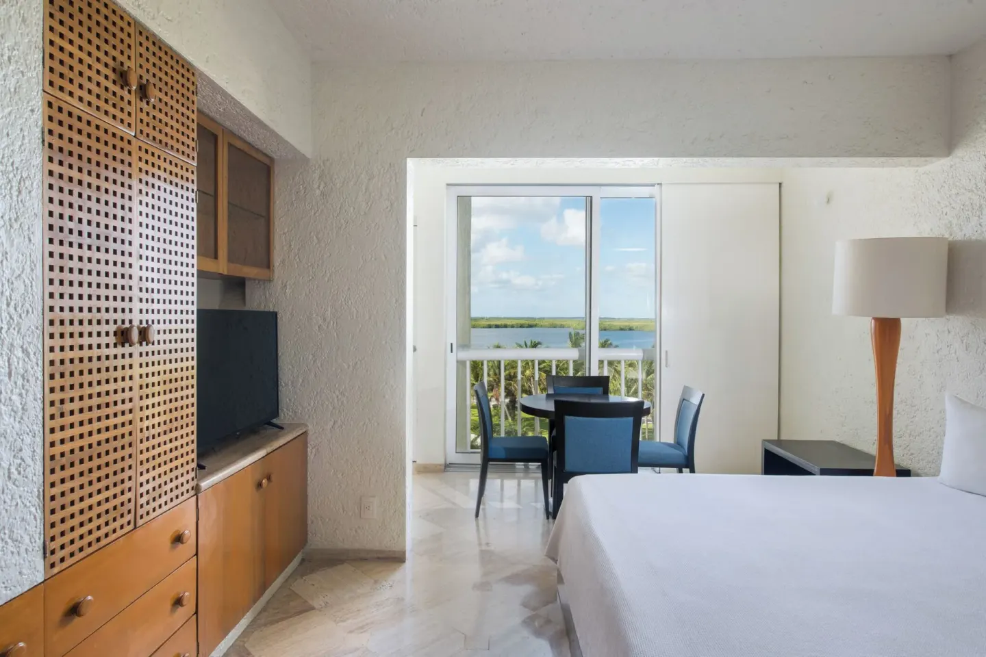 Classic Room with bed, storage cabinets and balcony view at Club Regina Cancun.