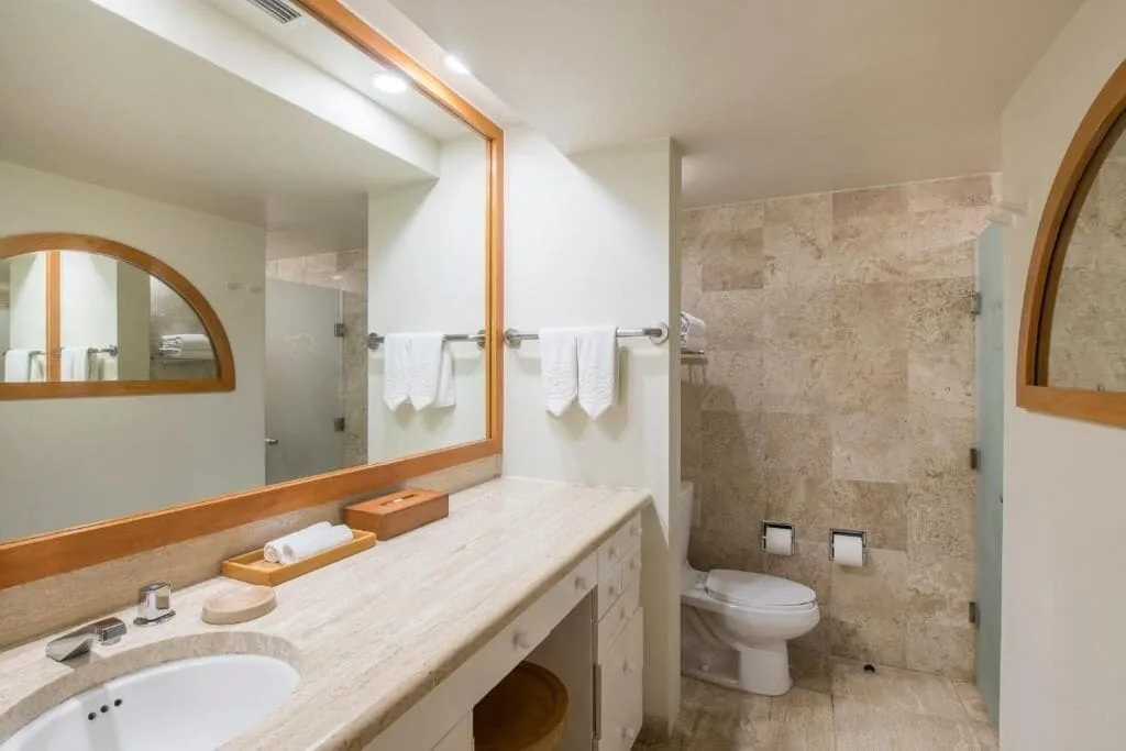 Classic Studio bathroom vanity, mirror, towels, and toilet at Club Regina Cancun.