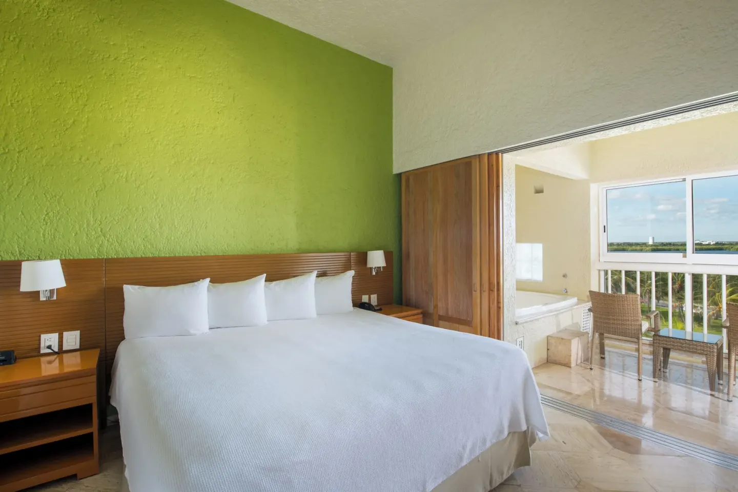 Classic Studio king bed beside a balcony sitting area at Club Regina Cancun.