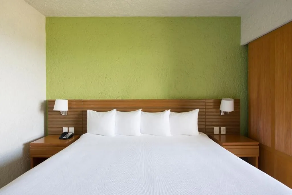 Classic Studio king bed with green accent wall at Club Regina Cancun.