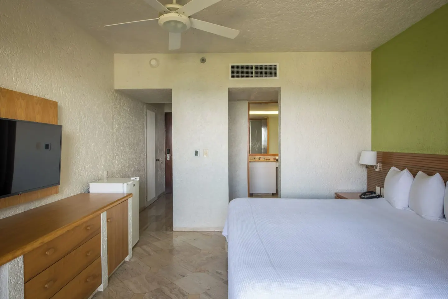 Classic Studio king bed, wall TV, dresser, and vanity entry at Club Regina Cancun.