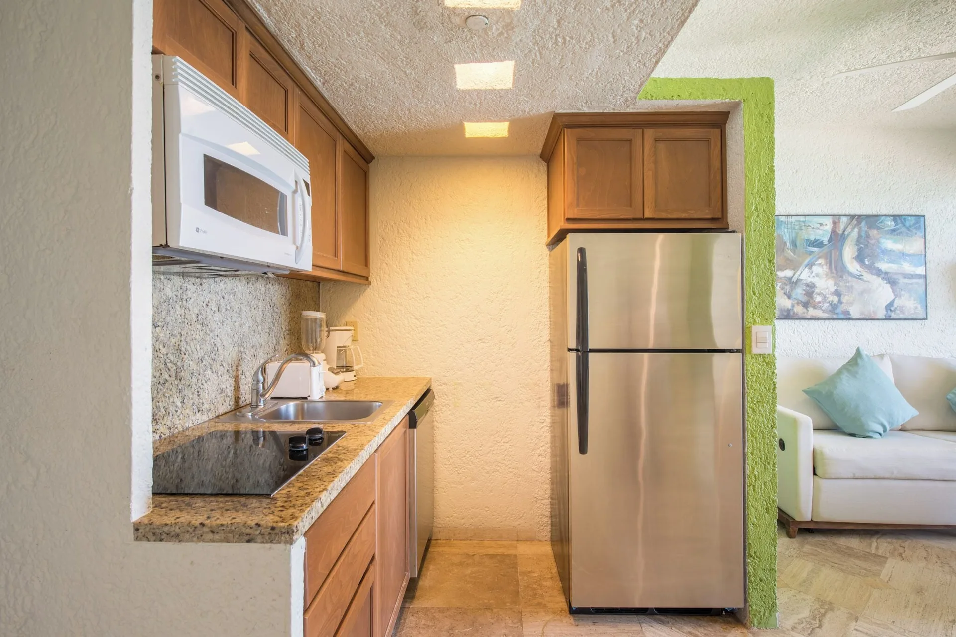 Deluxe Suite kitchenette with refrigerator and sofa at Club Regina Cancun.