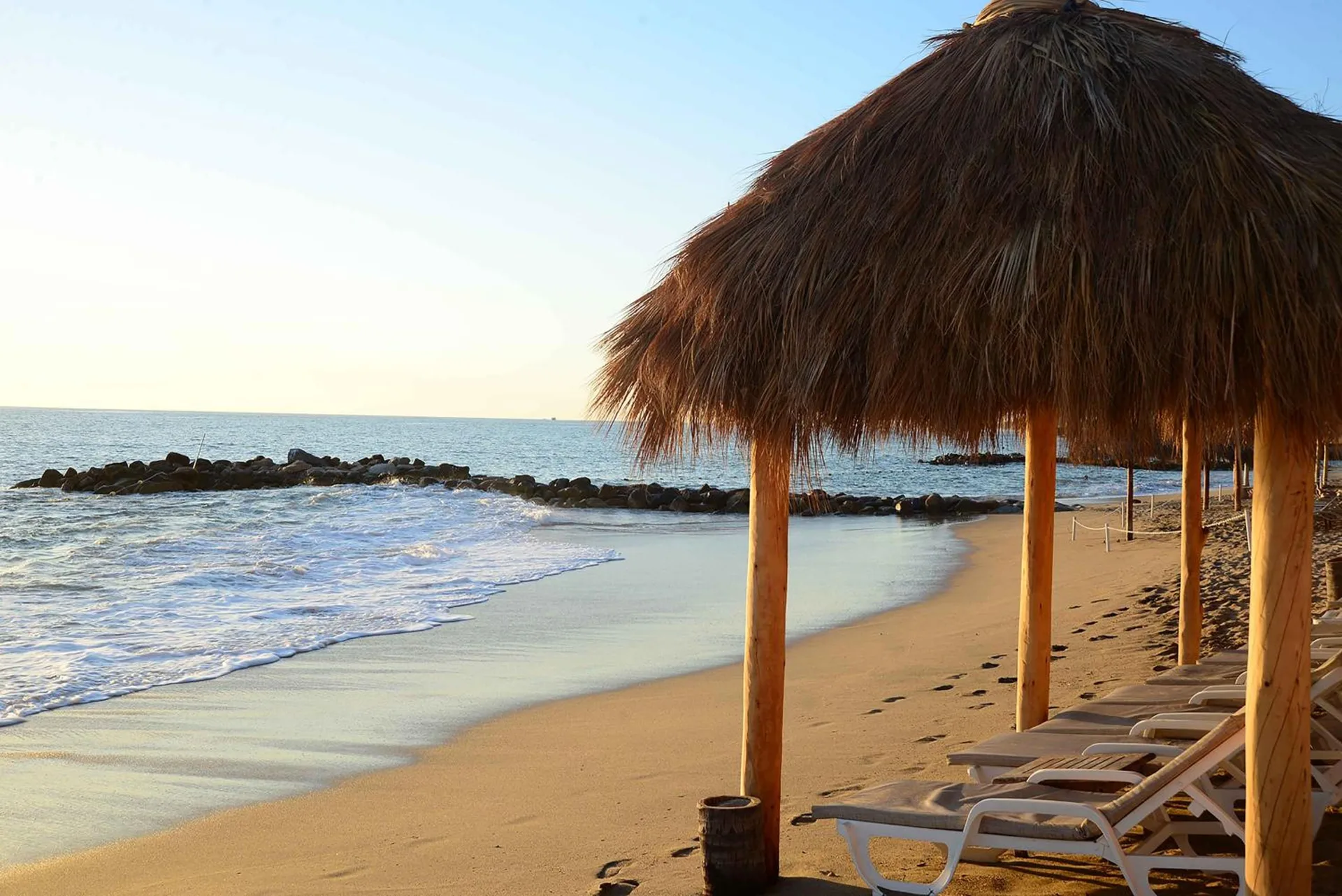 Beach palapa with lounge chairs by the ocean at Club Regina Puerto Vallarta.