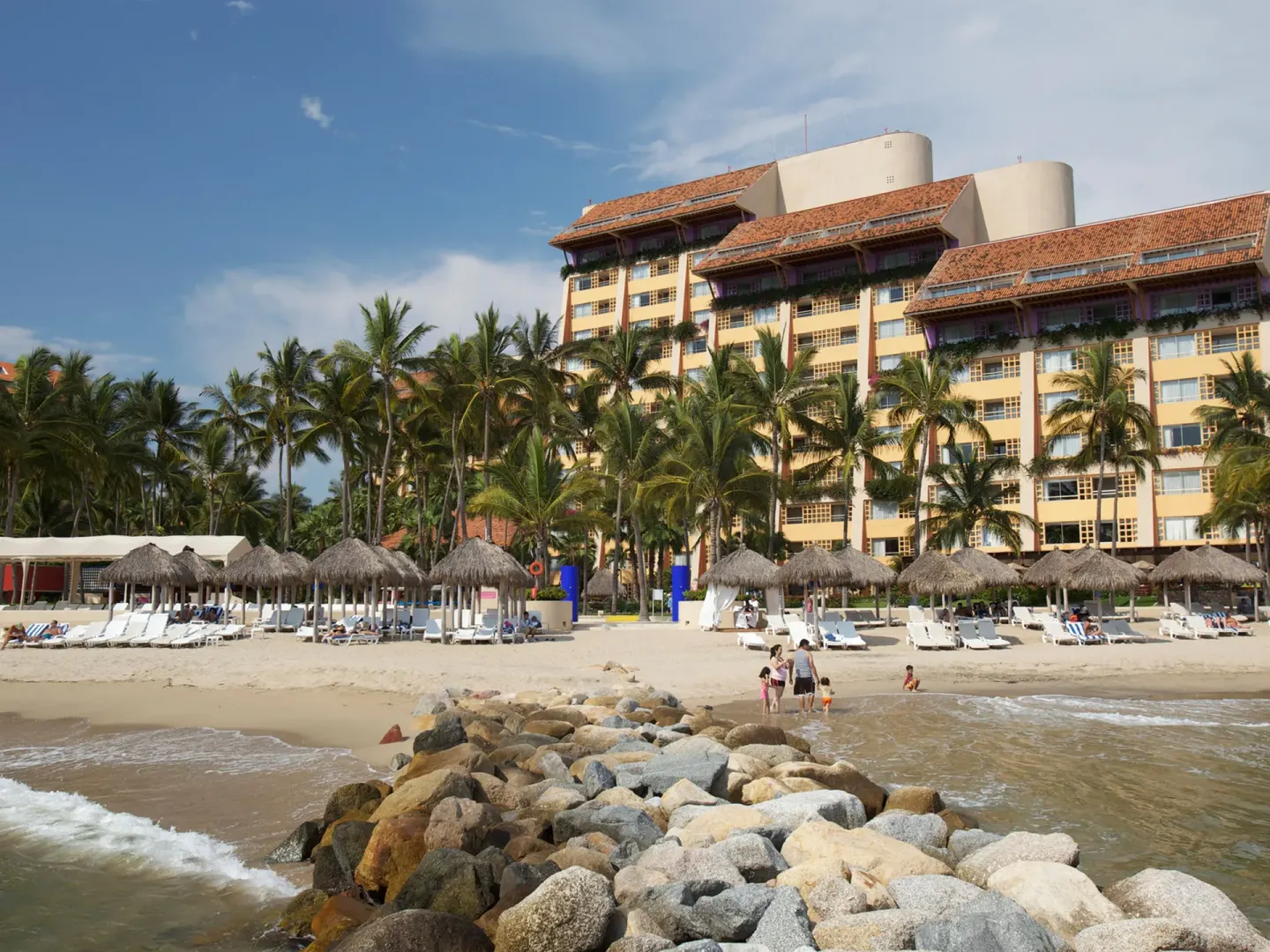 Beachfront resort buildings, palapas, and lounge chairs at Club Regina Puerto Vallarta.