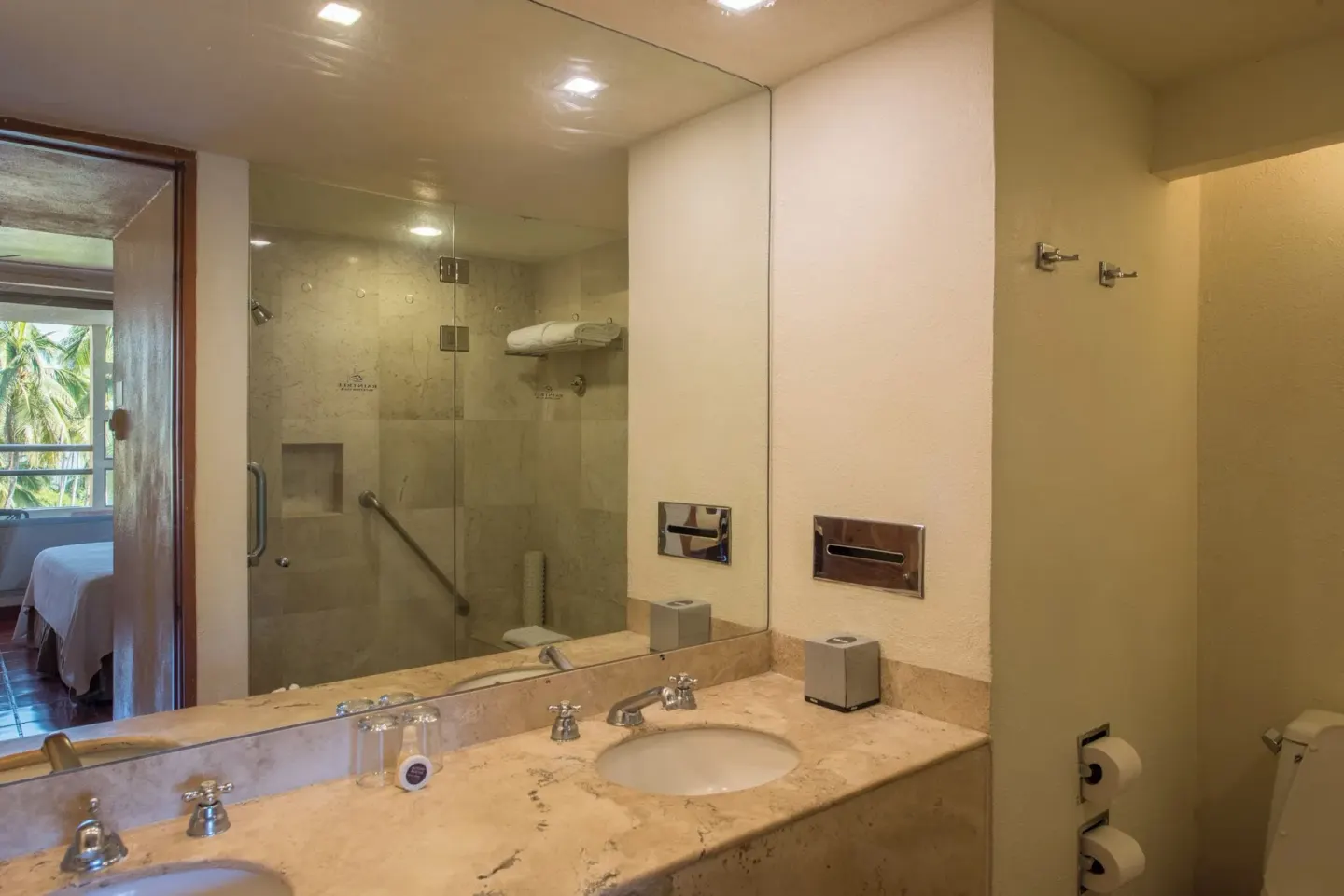 Bathroom vanity with mirror and shower reflected at Club Regina Puerto Vallarta.
