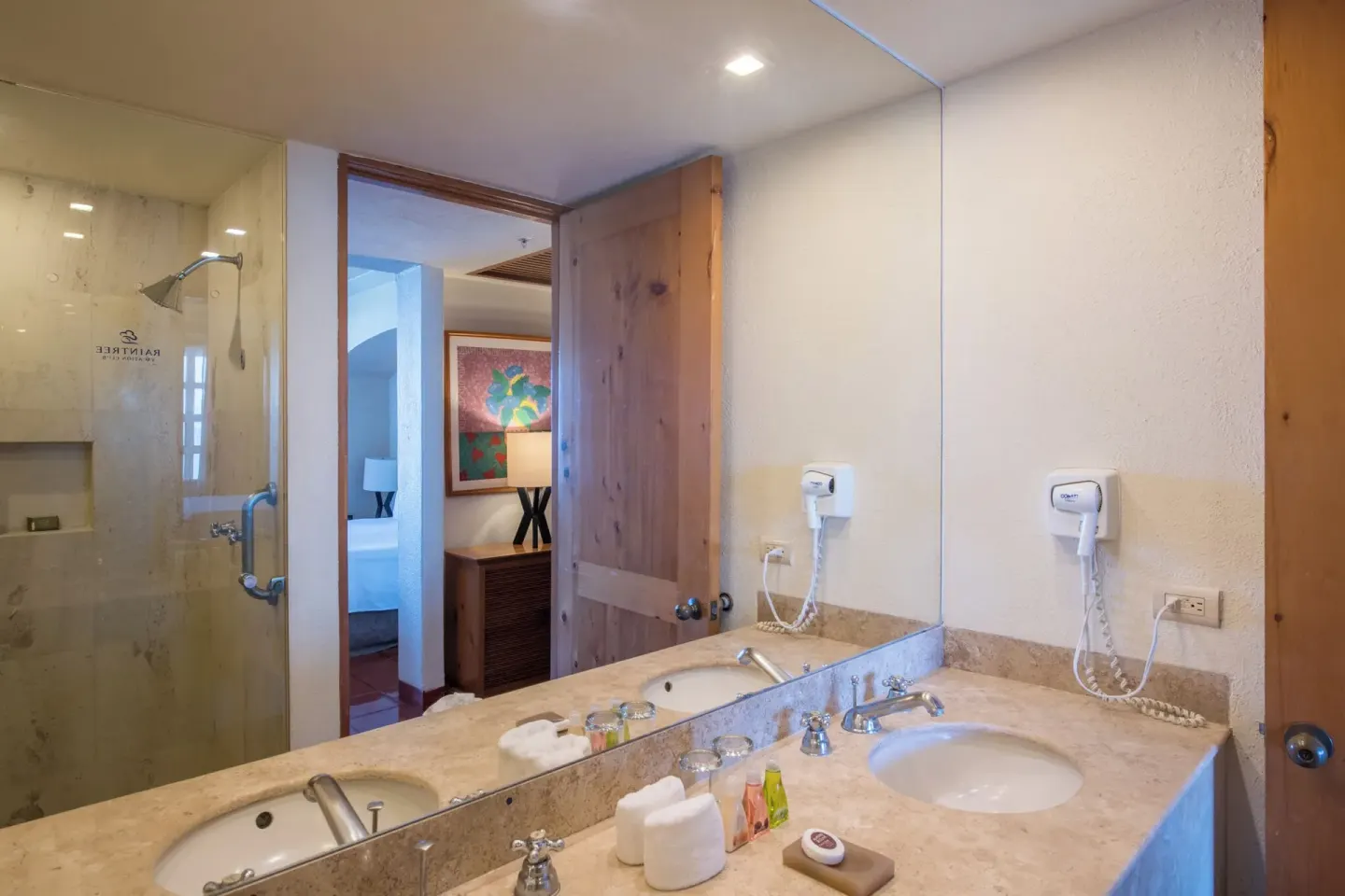 Bathroom sink and shower with bedroom doorway at Club Regina Puerto Vallarta.