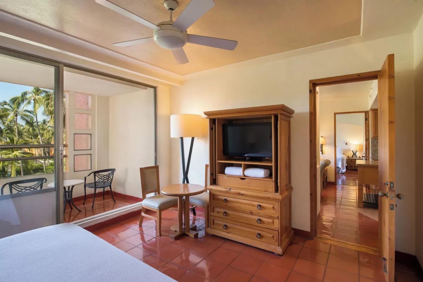 Guest room with king bed, TV cabinet, and balcony seating at Club Regina Puerto Vallarta.