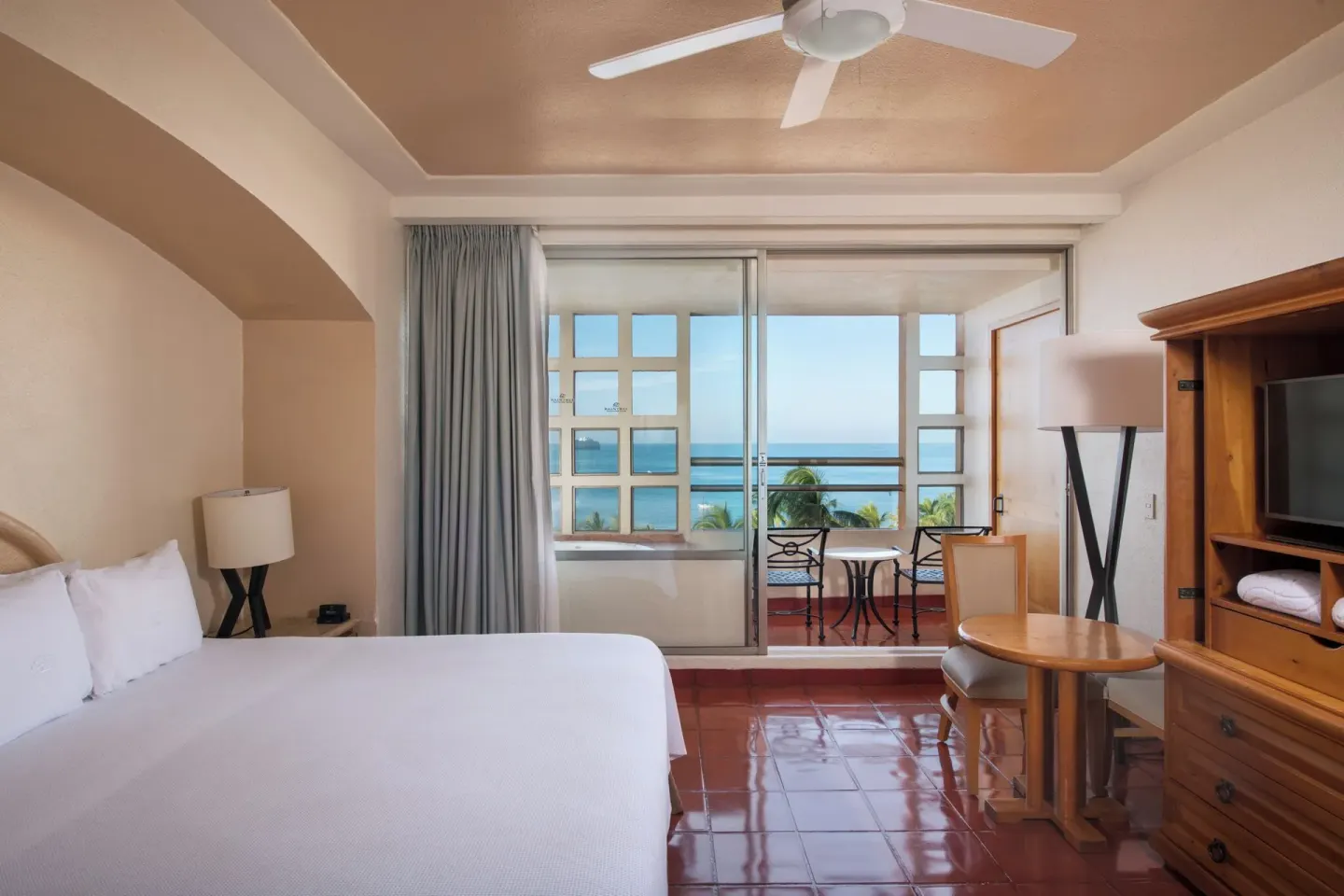 King bed guest room with balcony and ocean view at Club Regina Puerto Vallarta.