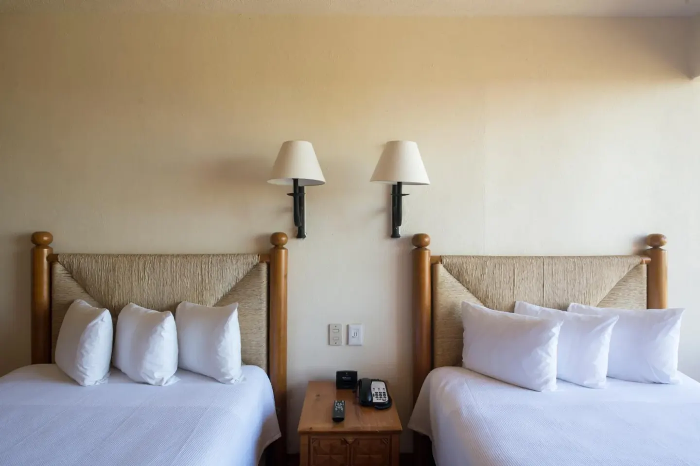 Guest room with two beds and wall lamps at Club Regina Puerto Vallarta.