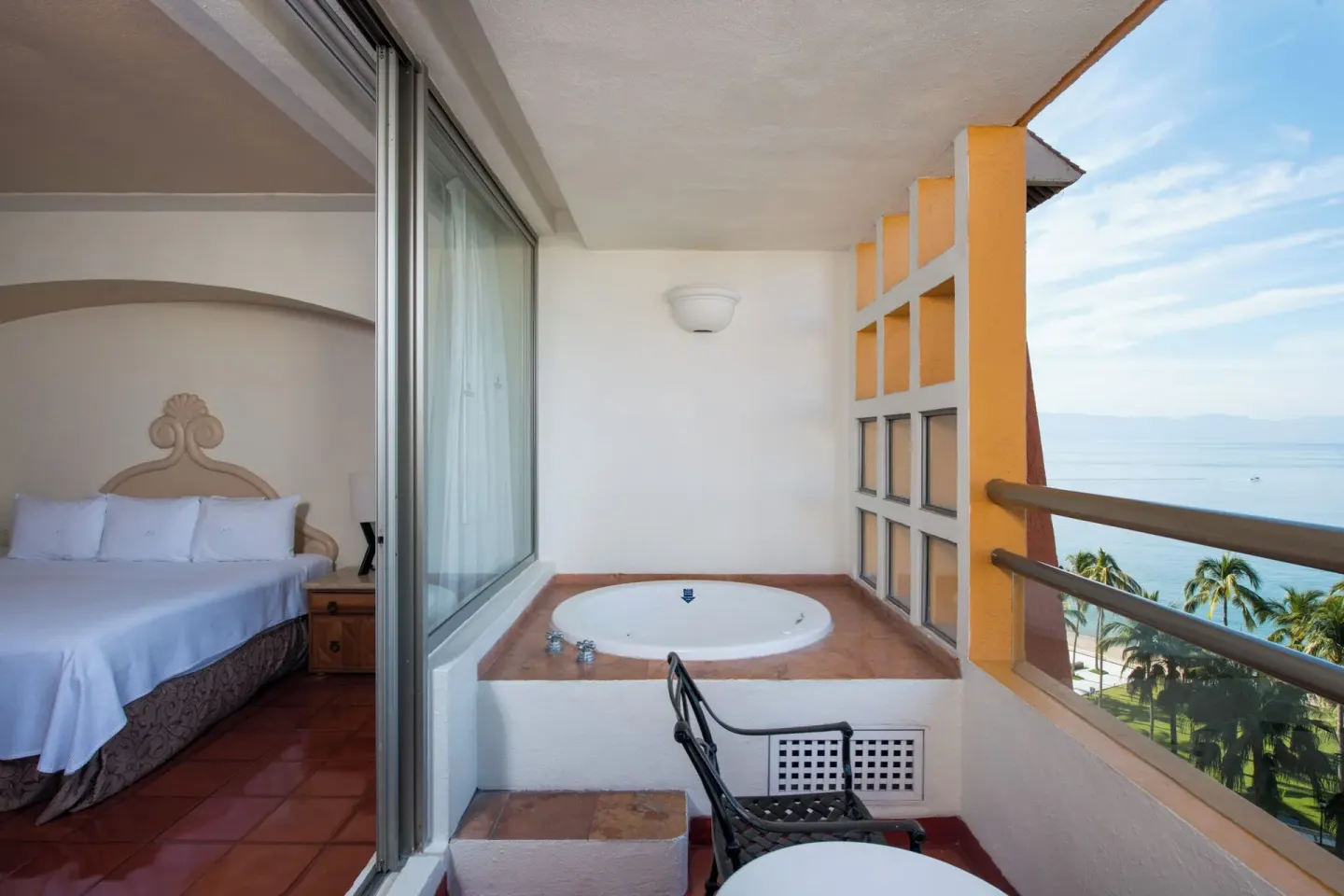 Ocean-view balcony with soaking tub beside a king bed at Club Regina Puerto Vallarta.