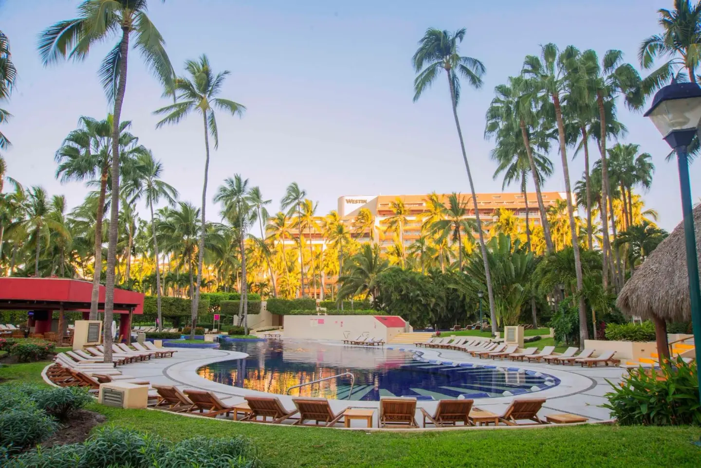 Palm-lined resort pool with lounge chairs at Club Regina Puerto Vallarta.