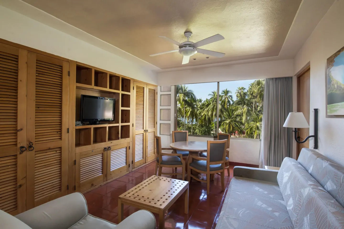 Living area with sofa, dining table, and palm view at Club Regina Puerto Vallarta.