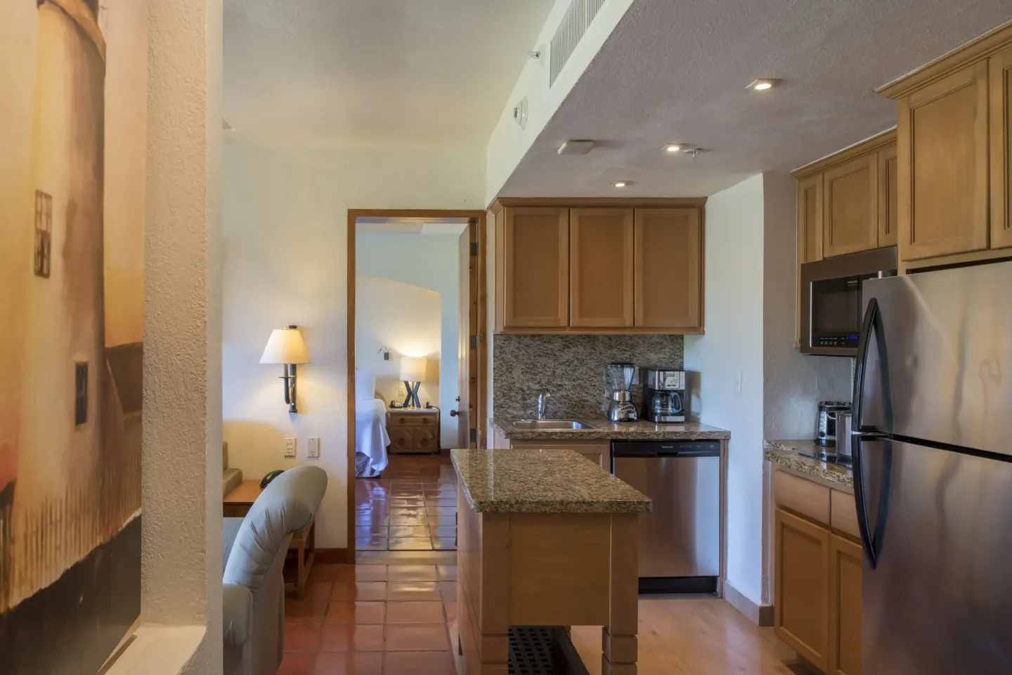 Suite kitchen with granite counters and a bedroom beyond at Club Regina Puerto Vallarta.