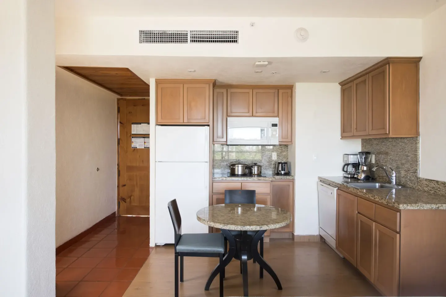 Suite kitchenette with refrigerator, cabinets, and round table at Club Regina Puerto Vallarta.