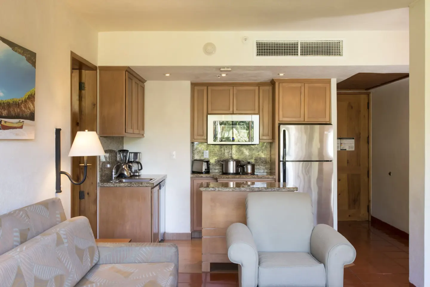Suite lounge with armchair, sofa, and kitchenette at Club Regina Puerto Vallarta.
