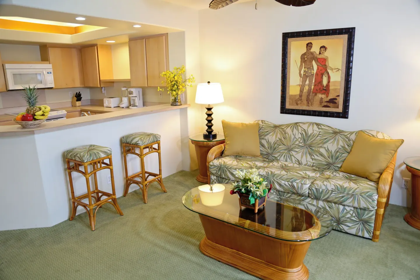 Living area with a sofa, glass coffee table, and kitchen at Club Wyndham Bali Hai Villas.