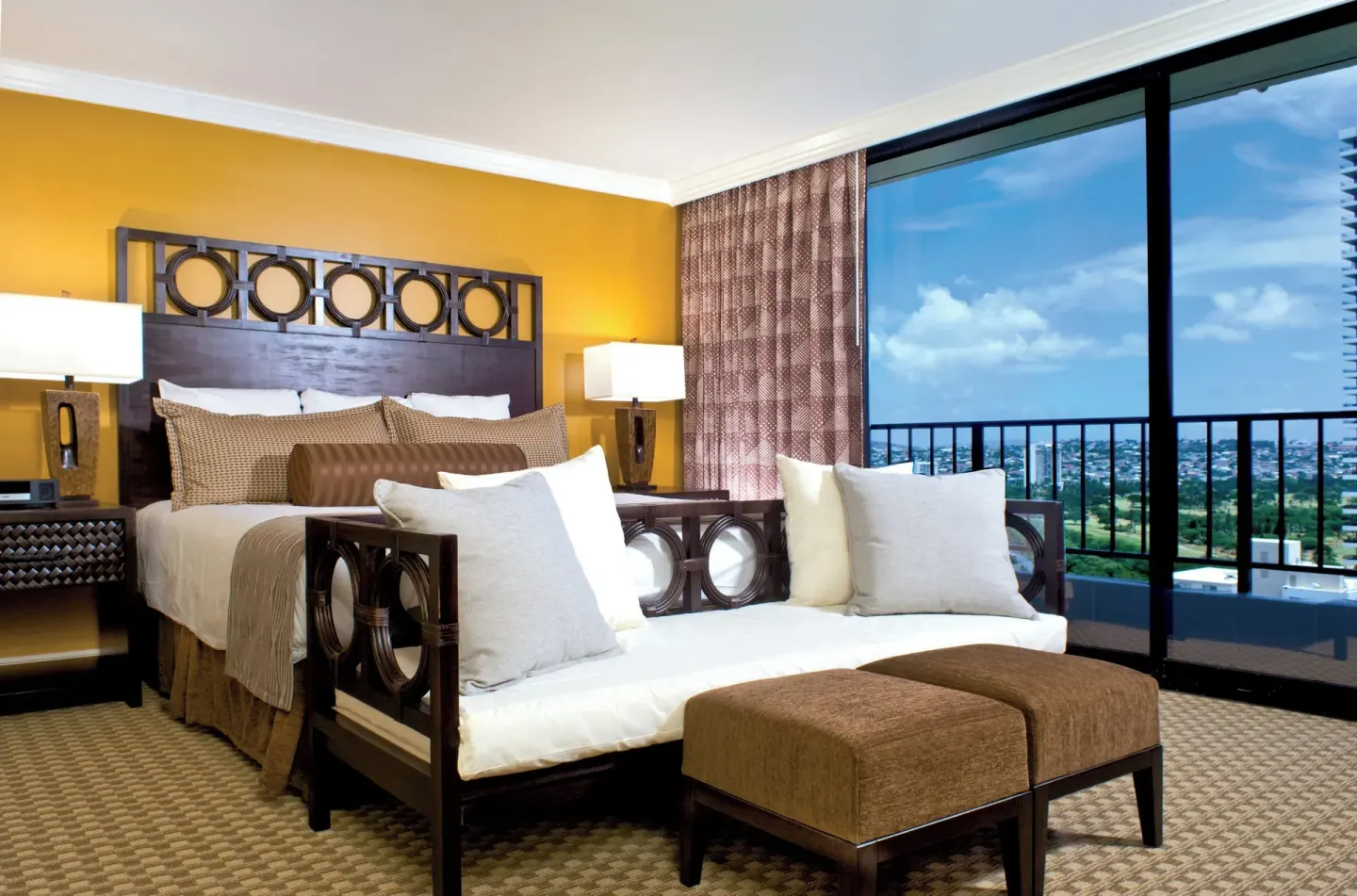 Guest room with king bed, daybed, ottomans, and balcony view at Club Wyndham Royal Garden at Waikiki.