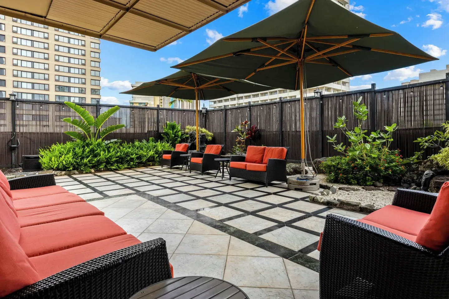 Outdoor patio with umbrellas and cushioned seating at Club Wyndham Royal Garden at Waikiki.